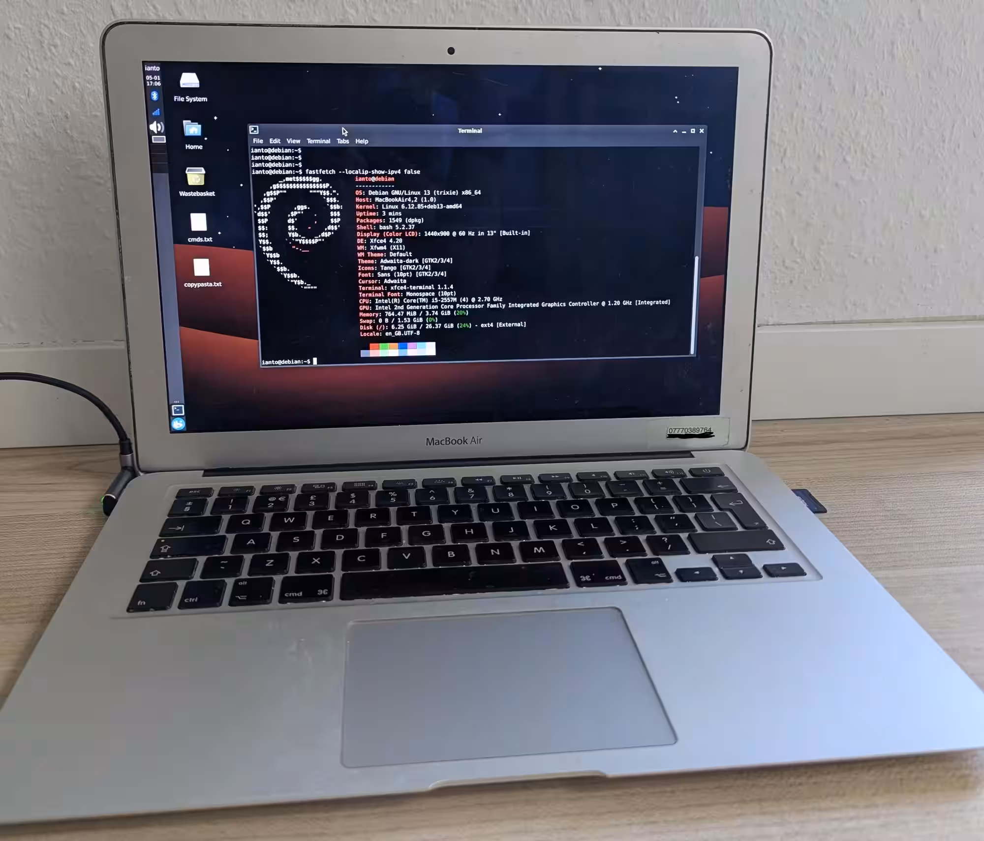 Photo of a macbook air with a debian logo on screen