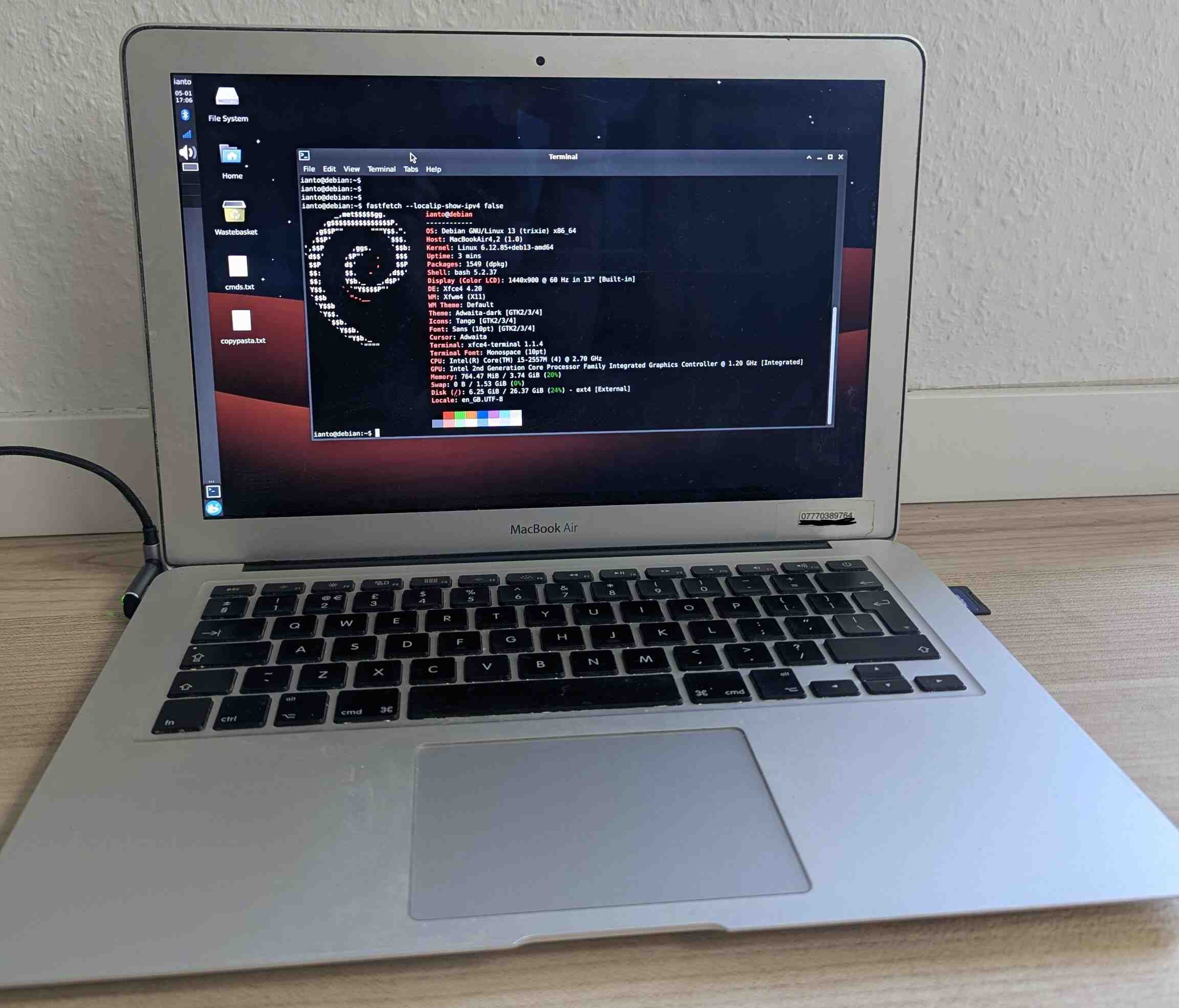 Photo of a macbook air with a debian logo on screen